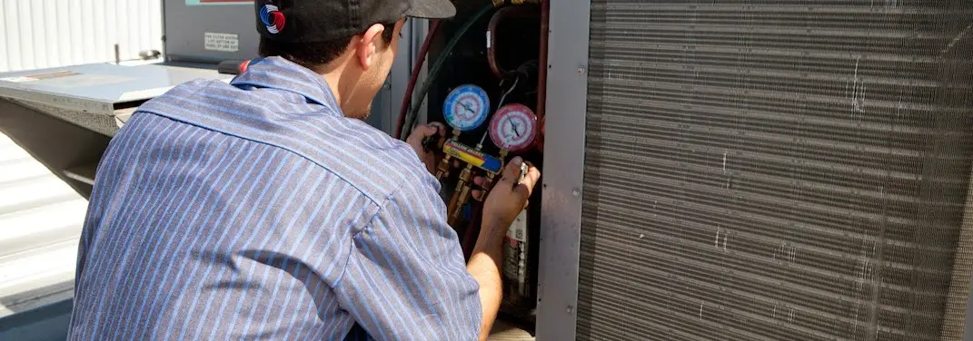 HVAC technician servicing a condenser unit in Winters